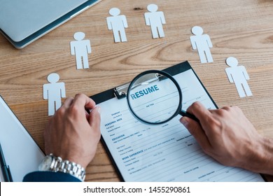 cropped view of man holding magnifier near clipboard with resume  - Shutterstock ID 1455290861