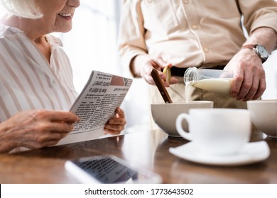 Cropped view of man pouring milk in bowl near smiling wife holding newspaper during breakfast in kitchen - Powered by Shutterstock