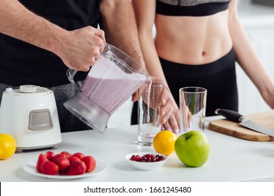 cropped view of man pouring smoothie in glass near sportive girl - Powered by Shutterstock