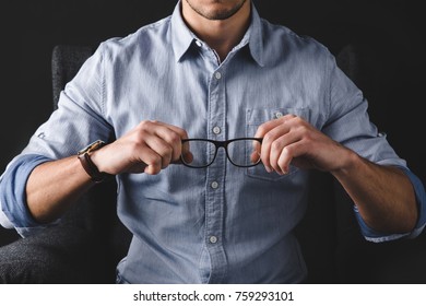 cropped view of man in shirt holding eyeglasses