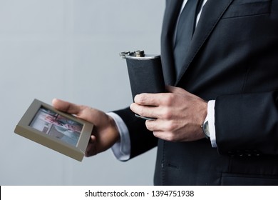 Cropped View Of Man In Suit Holding Flask And Photo In Frame 