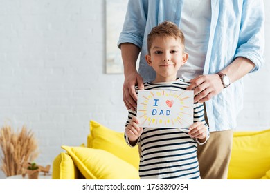 Cropped View Of Man Touching Shoulders Of Son Holding Handmade Fathers Day Greeting Card With Lettering And Heart Symbol