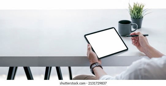 Cropped view of man using blank screen tablet sitting at white wooden table, banner panoramic view.