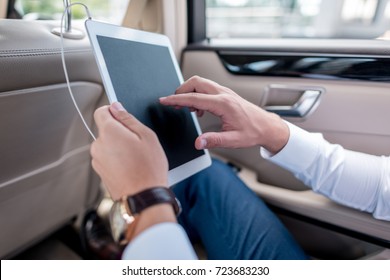 Cropped View Of Man Using Digital Tablet On Backseat Of Car