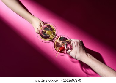 Cropped view of man and woman holding cocktails on pink background with shadow - Powered by Shutterstock