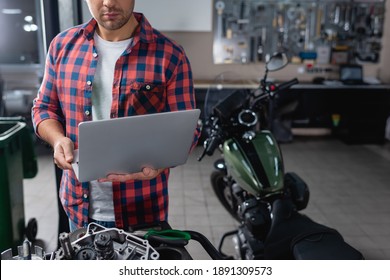 cropped view of mechanic using laptop near spare parts and motorcycle on blurred background - Powered by Shutterstock