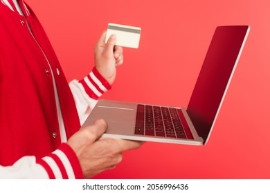 Cropped View Of Middle Aged Man Holding Laptop And Credit Card Isolated On Red