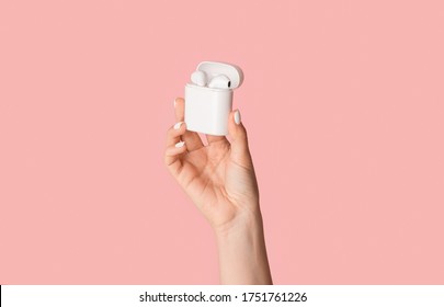 Cropped view of millennial girl holding modern earbuds in box on pink background, panorama