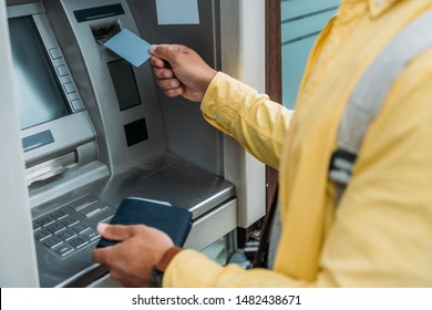 Cropped View Of Mixed Race Man Putting Credit Card In Atm Machine While Holding Wallet 