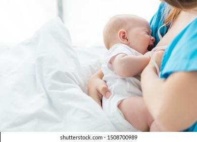 cropped view of mother breastfeeding her baby in hospital 