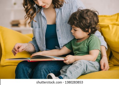 Cropped view of mother and son reading book together
