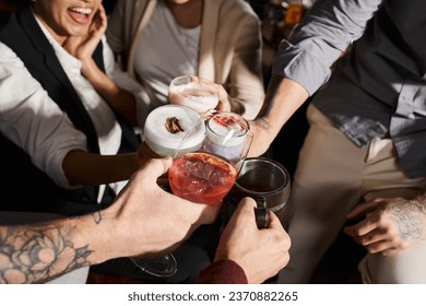 cropped view of multiethnic colleagues clinking glasses with delicious cocktails in bar, party time - Powered by Shutterstock