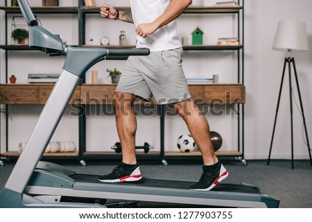 cropped view of muscular sportsman running on treadmill 