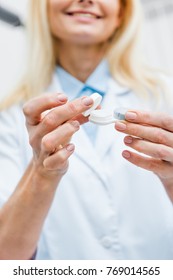 cropped view of optician in white coat holding contact lens