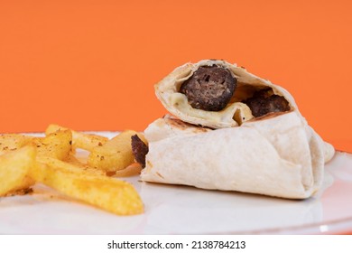Cropped view of plate of wrap and french fries shot from side or angle with selective focus on orange background in isolated setting.
Image of wrap meal and french fries.