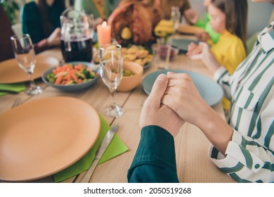 Cropped view portrait of adorable dreamy family holding hands praying appreciating eating lunch at home indoors