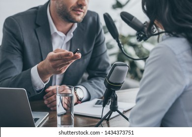 cropped view of radio host gesturing while interviewing businesswoman in broadcasting studio - Shutterstock ID 1434373751
