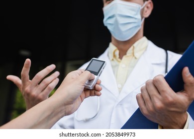 Cropped View Of Reporter Holding Voice Recorder Near Doctor In Medical Mask Gesturing During Interview