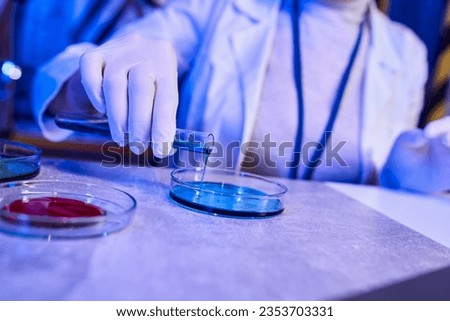 cropped view of scientist pouring liquid in petri dish, exploring extraterrestrial life