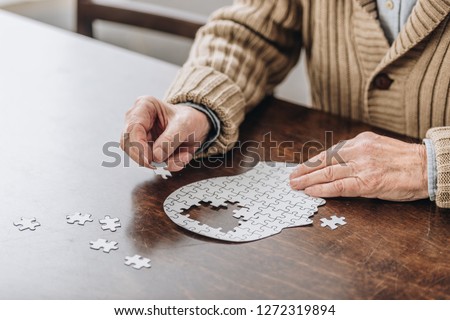 cropped view of senior man playing with puzzles 