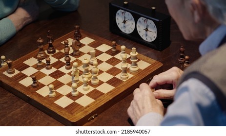 Cropped View Of Senior Men Playing Chess Near Blurred Timer