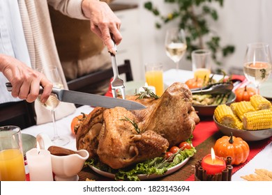 Cropped View Of Senior Woman Cutting Turkey On Table During Thanksgiving Celebration