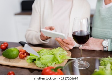 cropped view of senior women using smartphone near vegetables on table - Powered by Shutterstock