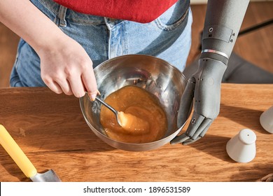 Cropped View Of Serene Young Woman With Implant Arm Holding Spoon At The Plate With Eggs And Beat It. Healthy Food, Cooking At Home And Dieting Concept. Stock Photo