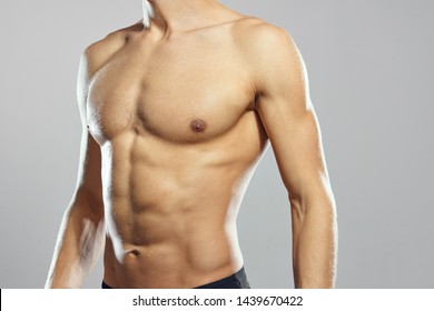 Cropped view of sexy bodybuilder gray background pumped torso biceps              