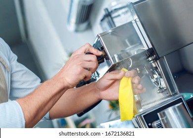 Cropped view of skilled young adult barista working in restaurant, cleaning professional coffee machine, using cloth towel - Powered by Shutterstock