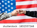 cropped view of soldier fist bumping with civilian man near american flag on blurred background