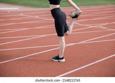 Cropped View Of Sportswoman In Black Bike Shorts Stretching Leg On Stadium