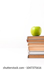 Cropped view of stack of books with apple on top isolated on white