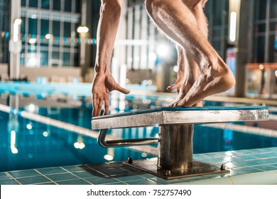 cropped view of swimmer standing on diving board ready to jump into competition swimming pool 