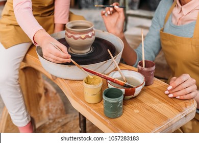 cropped view of teacher and kid painting ceramic pot with brushes in workshop - Powered by Shutterstock