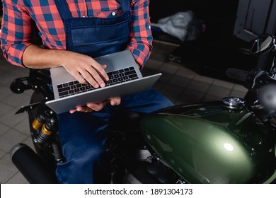 cropped view of technician using laptop while sitting on motorbike in workshop - Powered by Shutterstock