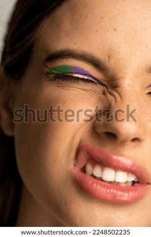 Cropped view of teenage girl with bright visage grimacing isolated on grey