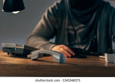 Cropped View Of Terrorist Sitting At Table With Telephone