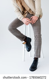 Cropped View Of Trendy Man In Grey Trousers And Black Boots Sitting On Stool On Grey