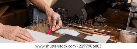 cropped view of typographer cutting paper with knife in print center, banner