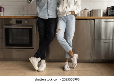 Cropped view unrecognizable African hipster couple in stylish casual clothing wear sport shoes standing on tiled floor in cozy remodelled modern kitchen. Furnishing, new house, renters family concept