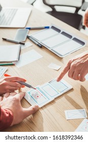 Cropped view of ux designers developing mobile app with layouts on table