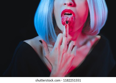 Cropped View Of Vampire Woman Licking Her Middle Finger Isolated On Black