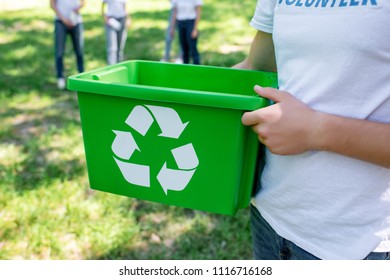cropped view of volunteer holding green recycling box in park   - Shutterstock ID 1116716168