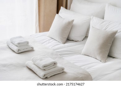 Cropped view of white bedclothes and towels on bed in comfortable hotel room, hypoallergenic pillows, personal comfort idea, bedding concept, bathroom details - Shutterstock ID 2175174627