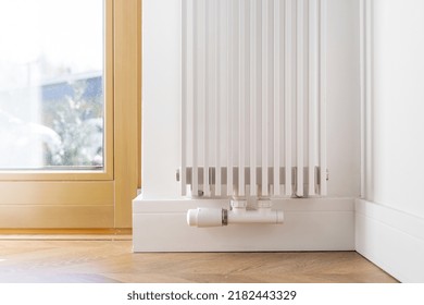 Cropped View Of White Stylish Radiator In Contemporary Living Room With Wooden Floor. Energy Consumption. Central Heating Installation. Heat Transfer Process