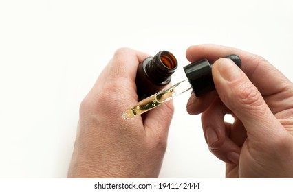 Cropped View Of Woman Applying Liquid From Glass Bottle, Woman Age Forty Plus. Apply A Moisturizer With Tea Tree Oil To The Skin.