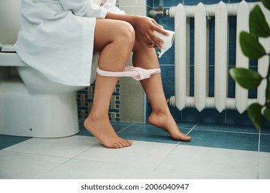 Cropped View Of Woman In Bathroom Sitting On Toilet With Toilet Paper In Hand And Panties Deflated. Closeup, Healthcare Concepts.