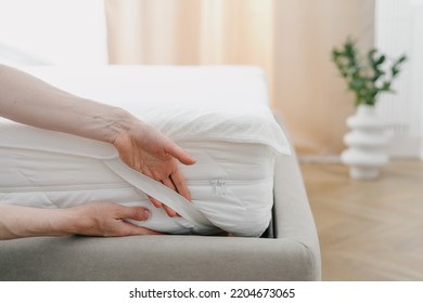 Cropped view of woman change waterproof bedding topper on orthopedic mattress. Maid showing how to make bed and fix the sheet corner with rubber band. Housekeeping and housework concept - Shutterstock ID 2204673065
