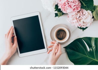 cropped view of woman hand with coffee cup and digital tablet with blank screen on tabletop with hortensia flowers  - Powered by Shutterstock